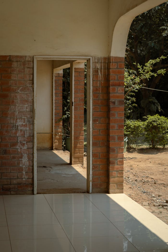 A sunlit corridor with brick walls leading to an outdoor garden area in Blantyre, Malawi.
